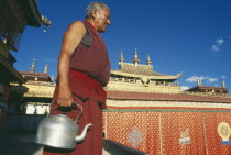 Monk carrying kettle on the roof of the temple