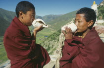 Two monks calling other monks to prayer by blowing into conch shells