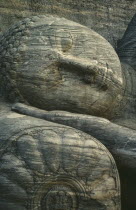 Stone carved reclining Buddha detail of head lying on hand