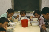 Family eating noodles at a table in the street