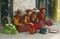 Four monks seated and chanting in the street