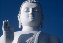 White Buddha statue detail of head shoulders and hand against blue sky