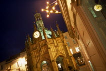 Angled view of The Cross at night  with star shaped Christmas light attached to nearby building with clock reflected in glass window. European Great Britain Nite Northern Europe UK United Kingdom Xma...