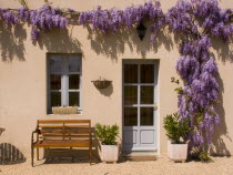Wisteria frames the front door and window of this picturesque apartment in the town of Les Forges. Two plant pots either side of the door and a bench beneath the window.