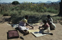 Woman and children sorting drying beans in Mozambican refugee camp.