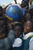 Children holding papier mache globe teaching aid made by PAMET from recycled materials.