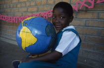 Portrait of child holding papier mache globe teaching aid made by PAMET from recycled materials.