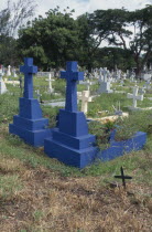 Blue painted crosses for those who died at sea in graveyard near Port Louis.
