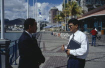 Two businessmen in conversation on the town waterfront.