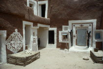 Traditional mud architecture decorated with bas relief motifs of applied gypsum  white and red clay.  Small child standing in shadow of corner of building. West Africa