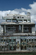 Part view of Mahafaly highly decorated tomb with carved effigy of aeroplane on roof.