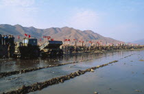 Juche people in a line reparing flood dykes with red flags fyling and mountains behind themJuche  pronounced /t.ut..e/ in Korean  approximately "joo-cheh"  is the official ideology of North Korea  an...