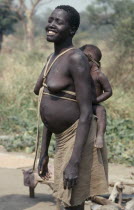 Uduk refugees from Sudan.  Smiling pregnant woman carrying baby on her back in cloth and wood sling.  Note scarification on stomach.