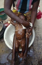 Cropped shot of mother washing baby girl in bowl in village near Sanonecleanhygiene