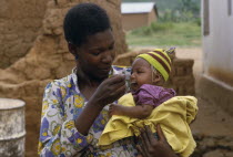 Mother feeding baby daughter with a spoon.