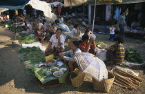 Vendors behind fruit and vegetable stalls