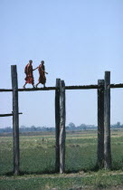 Monks walking aross the wooden Amarapura Bridge over the flood plain250yr old Burma