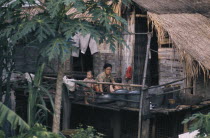 Mother bathing children outside stilt house