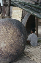 Boat building. Boy sat under bamboo