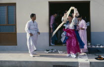 Female Shaman in a trance at a wedding waving cloth above her head with people looking on Mudang whose role it is to act as a intermediary between the living and spirit worlds