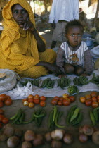 Woman and child behind market stall selling fruit and vegetables