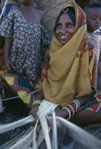 Woman making mats with children standing behind herAdi Keshi camp fro displaced people population 36.000