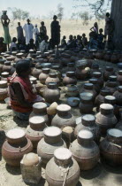 Woman selling vessels of Marissa Beer made from Sorghum and millet at Chadian Refugee market