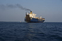 Container ship leaving Tema port emitting stream of thick black smoke from central funnel.West Africa  Air pollution  vessel