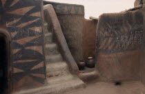 Traditional mud architecture.  Steps to flat roof where crops are dried and kitchen area.  Walls painted with broken calabash pattern in red and black.Sirigu village.  West Africa