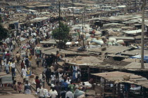 Busy market square with traffic  crowds of people and tin roofed open sided stalls. Asante West Africa