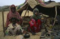 Beja nomad Beni Amer tribeswomen and child outside tent in refugee settlement.