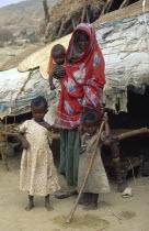 Beni Amer nomad refugee woman and children outside tent in desert camp with circular prayer mat on roof made from woven palm leaves or Birrish.