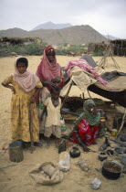 Beni Amer nomad refugee women and children outside small  makeshift tent in desert camp.