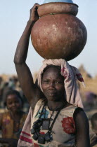 Chadian refugee woman carrying water pot on her head.