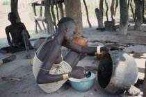 Dinka woman cooking with oil from shea butter fruit.