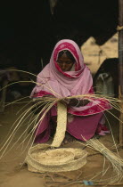 Eritrean woman in Gadum Gafriet refugee camp making birrish matting woven from palm leaves and used for tents and prayer mats