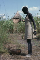 Dinka girl winnowing millet.