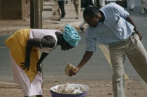 Woman selling Cashew nuts to a man along the road side
