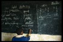 Boy in classroom writing in English on chalk board
