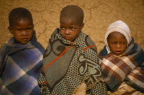 Three children wrapped in blankets