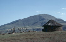 Circular straw roofed hut with mountains behind