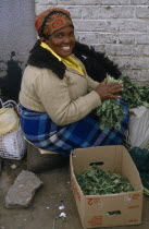 Woman at Maseru market selling greens from cardboard box