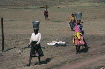 Women carrying buckets of water on their heads