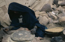 Tuareg woman grinding flour using two large circular stones for bread making. toureg
