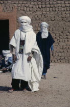 Two tuareg men dressed in loose cotton robes and head coverings suitable for desert heat. toureg