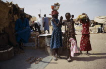 Young girls standing outside market stall belonging to their father.