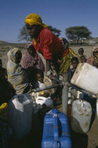 Woman filling water containers at standpipe in Somali camp.