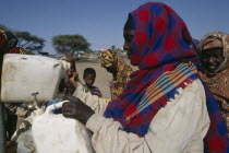 Woman filling water containers at standpipe in Somali camp.