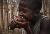 Child cupping his hands together drinking well waterAfrican Kids Western Africa Children