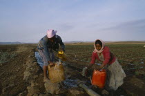 Women collecting water at irrigation pipe.